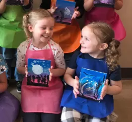 Two little girls holding their art they just painted.